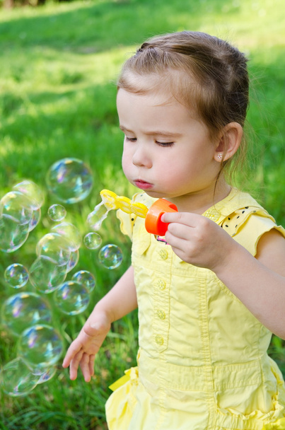 Portrait of little girl blowing soap bubbles - Foto, Imagem