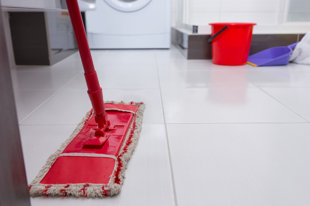 Colorful red mop on a clean white tiled floor - Photo, Image