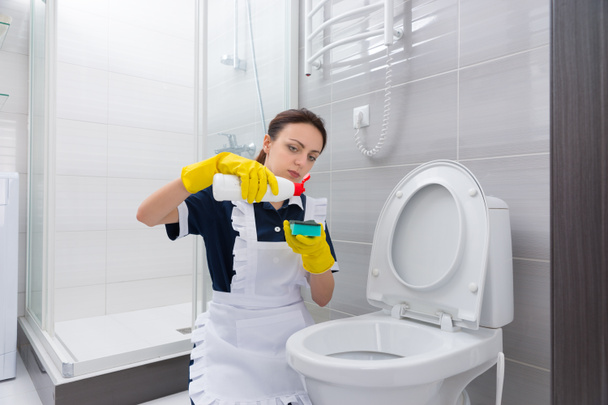 Maid putting cleaner on sponge above toilet - Foto, Bild