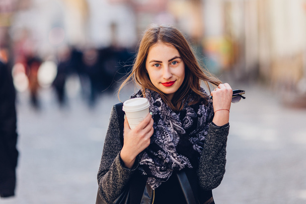 Young girl walking on the street with cup of hot coffee - 写真・画像