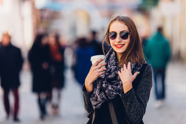 Young girl walking on the street with cup of hot coffee - Fotoğraf, Görsel