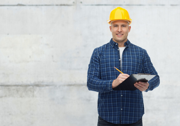 smiling male builder in helmet with clipboard - Photo, Image