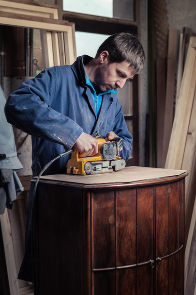 Carpintero restaurando muebles con lijadora de cinturón
 - Foto, imagen