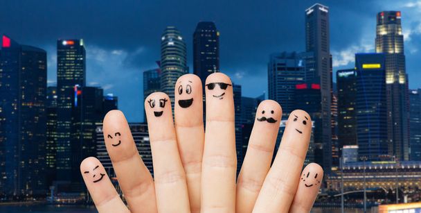 close up of fingers with smiley faces over city - Photo, Image