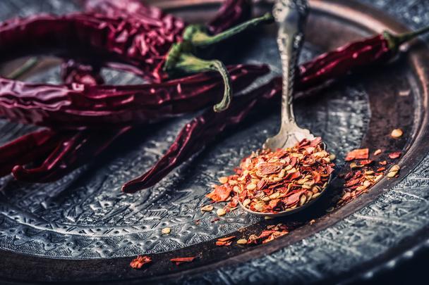 Chili. Chili peppers. Several dried chilli peppers and crushed peppers on an old spoon spilled around. Mexican ingredients - cuisine - Fotó, kép
