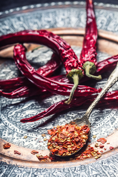 Chili. Chili peppers. Several dried chilli peppers and crushed peppers on an old spoon spilled around. Mexican ingredients - cuisine - 写真・画像