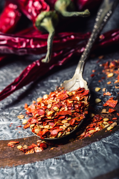 Chili. Chili peppers. Several dried chilli peppers and crushed peppers on an old spoon spilled around. Mexican ingredients - cuisine - Fotó, kép