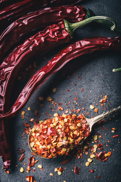 Chili. Chili peppers. Several dried chilli peppers and crushed peppers on an old spoon spilled around. Mexican ingredients - cuisine - Fotoğraf, Görsel