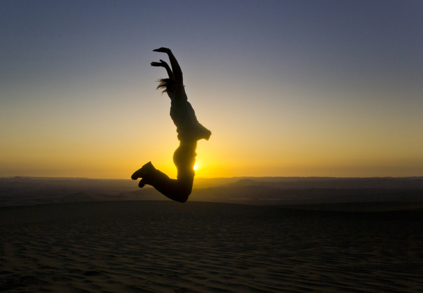 jumping man with hands up at sunset in desert - Foto, Bild