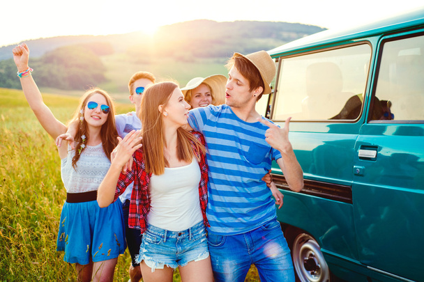 Young frieds with campervan, green nature and blue sky - Photo, Image