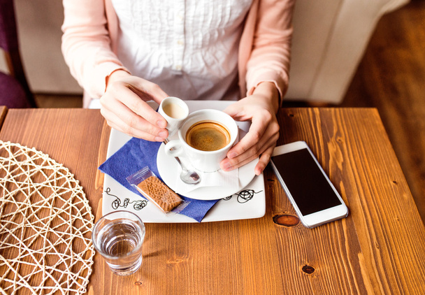 Unrecognizable woman in cafe drinking coffee, pouring cream in - Foto, immagini