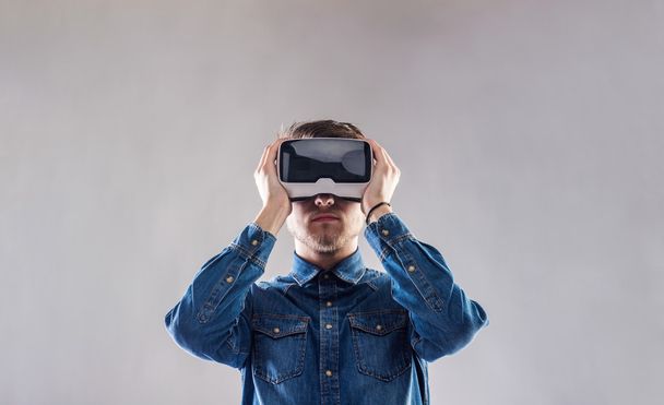 Man wearing virtual reality goggles. Studio shot, gray backgroun - Photo, Image