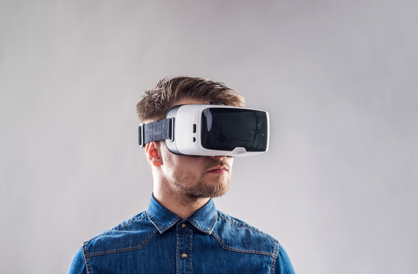 Man wearing virtual reality goggles. Studio shot, gray backgroun - Foto, immagini