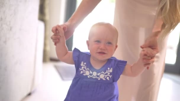 Mom helps baby daughter taking first steps - Materiaali, video