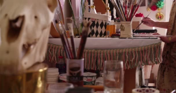 Artist painting on paper at a table in her studio - Filmati, video