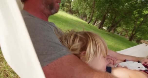 dad hugging his sons on hammock outside - Materiał filmowy, wideo