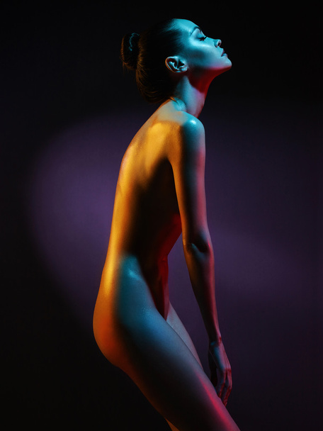 Elegant nude model in the light colored spotlights - Φωτογραφία, εικόνα