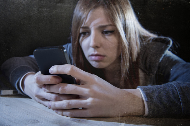 インターネットストーカー被害者がサイバーいじめストレスを悪用したように、心配して携帯電話に必死に見えるティーンエイジャーの女の子 - 写真・画像