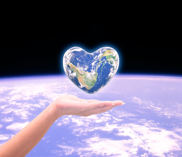 Mondo a forma di cuore con sopra le donne mani umane su natu offuscata
 - Foto, immagini