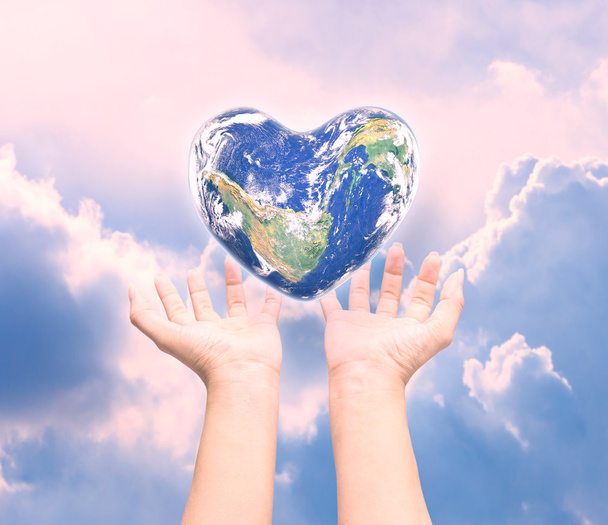 World in heart shape with over women human hands on blurred natu - Foto, Imagen