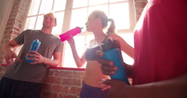 Счастливые молодые друзья пьют воду в спортзале
 - Кадры, видео