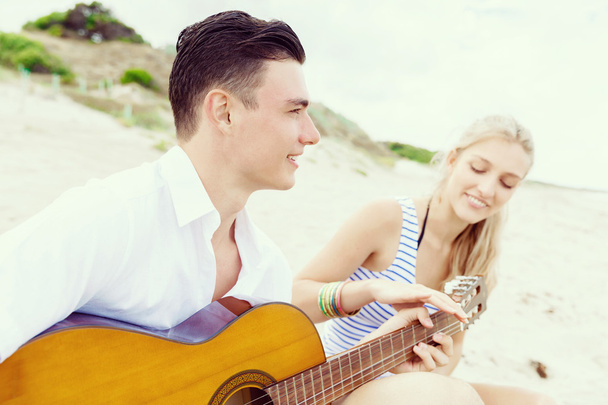 Young couple playing guitar on beach in love - Foto, immagini