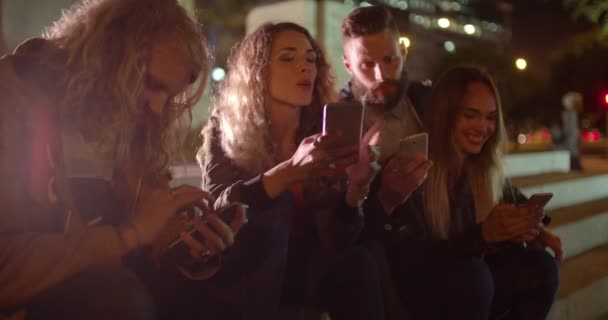 Freunde verbringen Zeit mit Smartphones auf Stufen nach draußen - Filmmaterial, Video