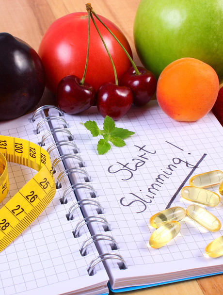 Frutas, suplementos de tabletas y centímetros con cuaderno, adelgazamiento y alimentos saludables
 - Foto, imagen