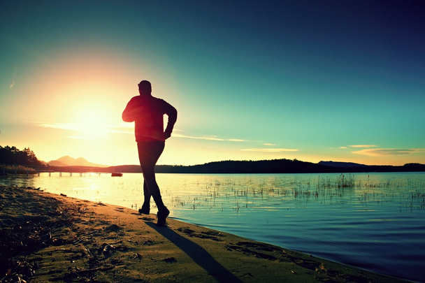 Αθλητής τρέχει στο καταπληκτικό ηλιοβασίλεμα καλοκαίρι κατά μήκος της ακτής στο άθλημα και υγιούς τρόπου ζωής - Φωτογραφία, εικόνα