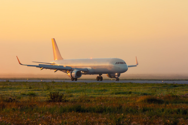Plane on the taxiway in the early foggy morning - Foto, imagen