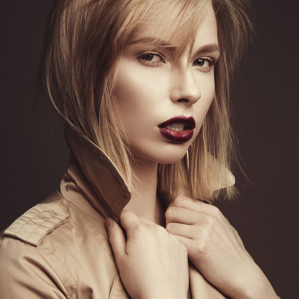 Beautiful blonde woman in a bright coat and dark lips, showing d - Valokuva, kuva