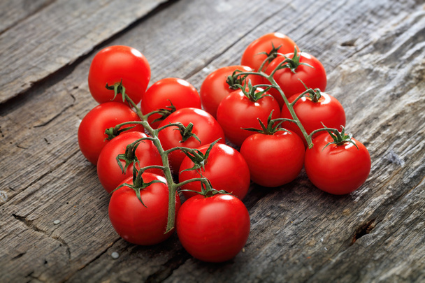 Two bunches of red cherry tomatoes, on wooden surface - Foto, imagen