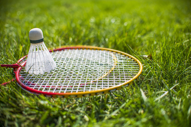 Shuttlecock and badminton racket on green grass - Fotografie, Obrázek