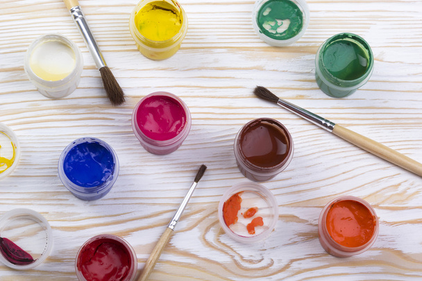 Gouache-verf en penselen op houten achtergrondkleur - Foto, afbeelding
