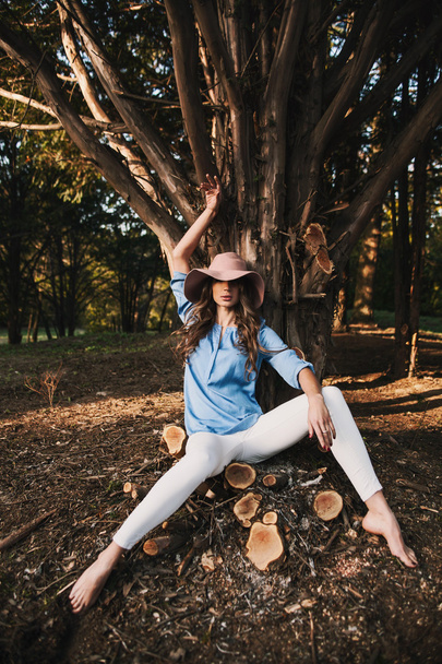Frau mit Hut sitzt im Wald - Foto, Bild