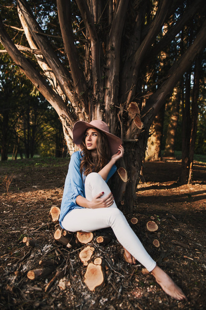 kobieta w kapeluszu siedzi w lesie - Zdjęcie, obraz