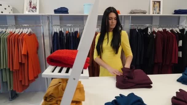 Woman Walking by Shop Takes a Red Sweater Tries it Choosing a Clothes Womenswear Shop Client Brunette Woman is Buying a Clothes Garments on a Trempels - Materiał filmowy, wideo