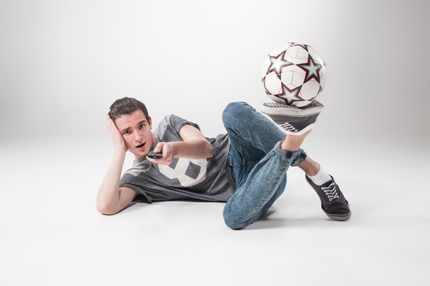 The portrait of fan with ball, holding  tv remote on white background - Фото, зображення