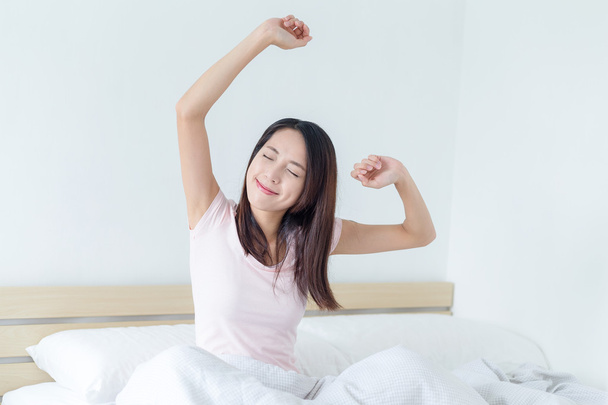 woman stretching in bed after waking up - Photo, Image