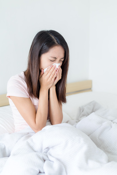 woman getting cold and sneezing on bed - Photo, Image