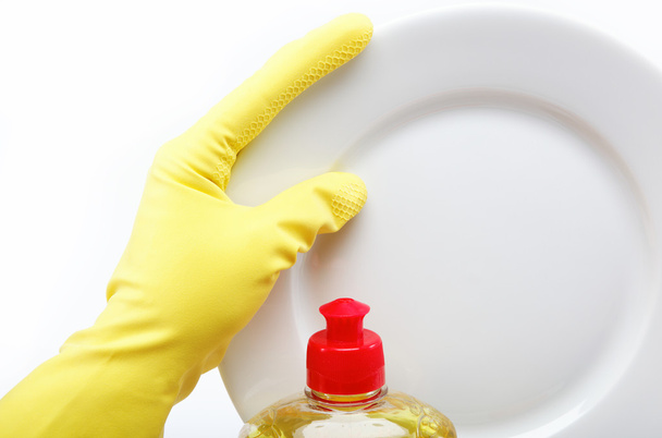 Hand in rubber glove with a plate and a bottle of detergent on a - Fotografie, Obrázek