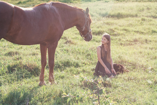 Girl and her horse on the sunlit field - Photo, Image