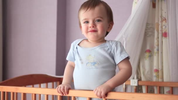 Little Boy Standing in the Crib, Smiles and Leans His Malnkimi Handles on the Railing Cot - Footage, Video