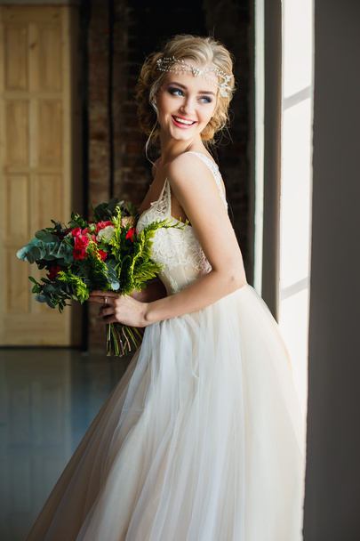 Belle mariée en robe de luxe magnifique tenant bouquet dans un espace loft. Photo de mariage moderne
 - Photo, image