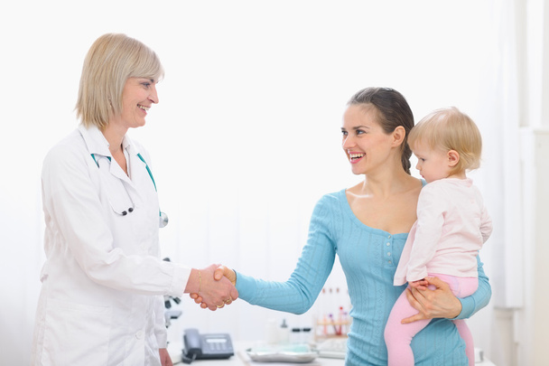 Grateful mom shaking hand to middle age pediatric doctor - Zdjęcie, obraz