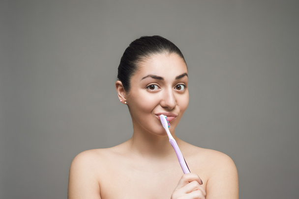 Jeune belle fille avec brosse à dents sur le fond gris
 - Photo, image