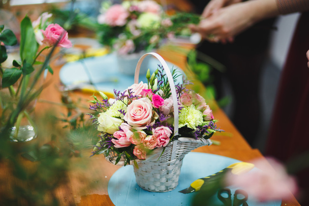 Floral workshop - florist makes a bouquet in a basket. Students florists work together. - Photo, Image