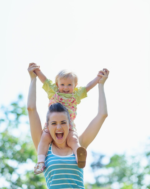 Happy mother with baby sitting on shoulders - Photo, Image