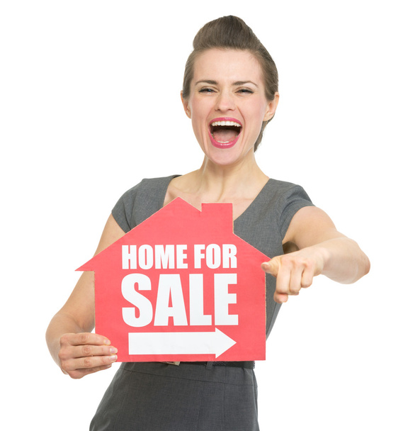 Smiling realtor showing home for sale sign and pointing on you - Fotoğraf, Görsel