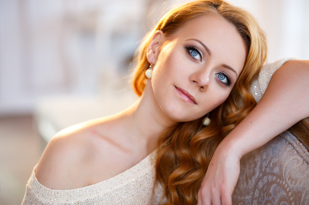 Młoda piękna kobieta w ciepły sweter w światło sypialni rano. Bliska portret, niebieskie oczy i naturalny makijaż - Zdjęcie, obraz